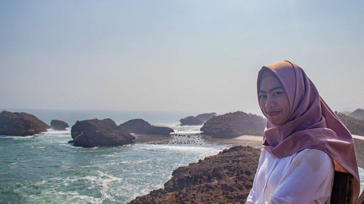 WISATA DI PACITAN - Seorang pengunjung berfoto dengan latar belakang gugusan karang di Pantai Kasap, Pacitan.