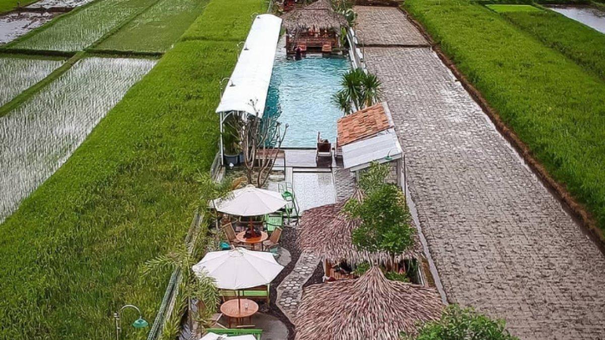 OBYEK WISATA KLATEN: Kolam memiliki desain memanjang dengan area duduk yang dilengkapi gazebo beratap jerami dan payung putih, memberikan tempat bersantai bagi pengunjung Pesona Alam Tirta Klaten