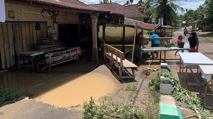 Al Fajri bersama keluarganya membersihkan lumpur di rumahnya pasca terendam banjir di Kampuang Galapuang, Padang Pariaman, Sabtu (5/10/2024). 