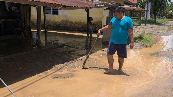 Al Fajri bersama keluarganya membersihkan lumpur yang menghinggapi rumahnya pasca terendam banjir di Kampuang Galapuang, Padang Pariaman, Sabtu (5/10/2024). 