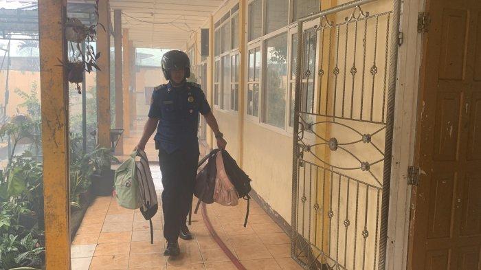 Petugas Damkar Padang mengevakuasi ransel siswa SMPN 8 Padang yang terbakar di Kecamatan Padang Timur, Kota Padang, pada Selasa (30/7/2024).