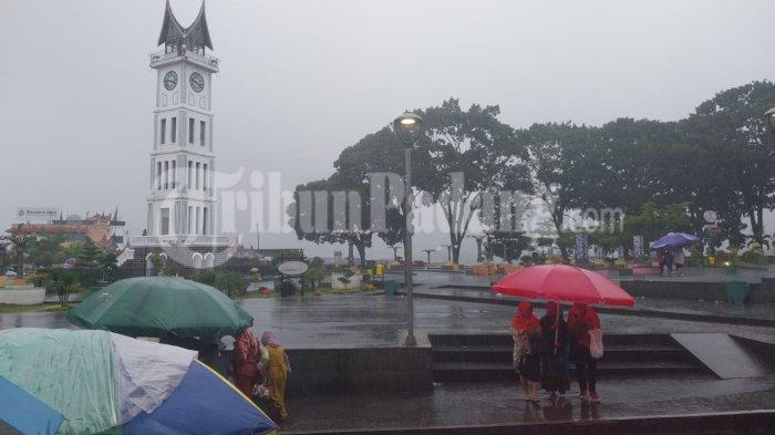 Pedagang di Bukittinggi sediakan jasa ojek payung kepada para pengunjung Jam Gadang, Minggu (23/7/2023).