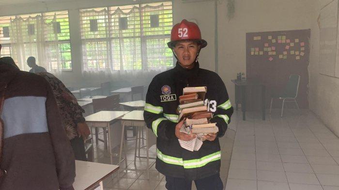 Petugas Damkar Padang mengevakuasi buku-buku di ruang kelas SMPN 28 Padang yang terbakar di Kecamatan Padang Timur, Kota Padang, pada Selasa (30/7/2024).
