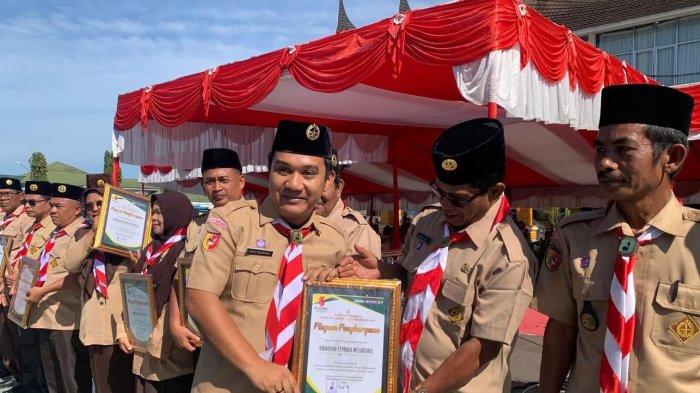Wakil Ketua Humas dan IT Randy Hendrawan saat menyerahkan piagam penghargaan kepada Ka.Mabiran Lembah Melintang Syaiful AM usai Apel Besar Hari Pramuka ke 63 di Halaman Kantor Bupati Pasaman Barat.