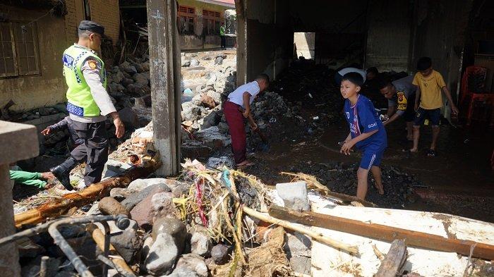 Siswa sekolah dan polisi bahu membahu membersihkan material banjir di Nagari Koto Tuo, Kecamatan IV Koto, Agam, Sumatera Barat, Senin (13/5/2024).
