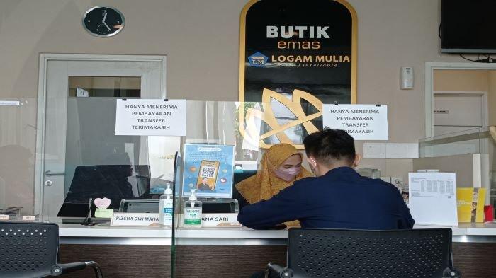 Petugas butik Antam tengah melayani konsumen yang membeli logam mulia.