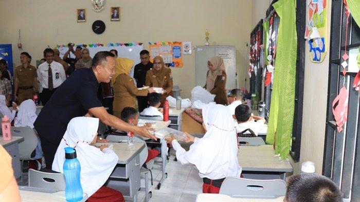 Kepala Dinas Pendidikan Kota Palembang, Adrianus Amri, saat membagikan makanan ke para siswa SD yang ada di Kota Palembang, Senin (6/1/2025).