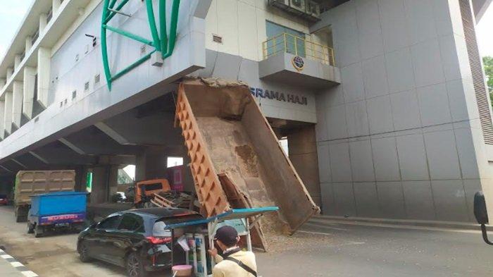Bak sebuah mobil dump truk nopol BA 8467 AU terbuka hingga membuatnya tersangkut di Jalan Letjen Harun Sohar di bawah stasiun LRT Asrama Haji, Sabtu (23/12/2023).