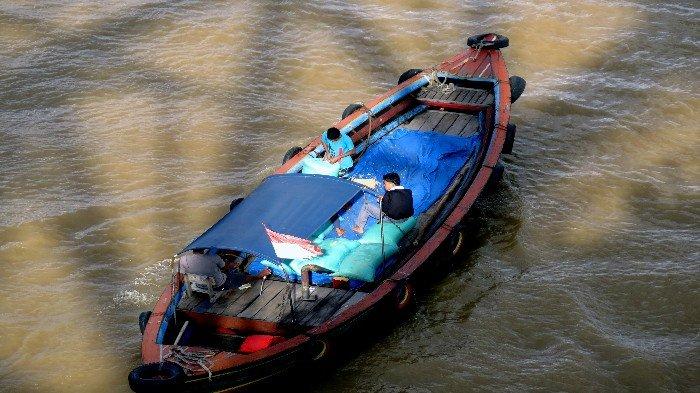 BAWA HASIL PANEN - Keluarga petani menggunakan perahu jukung bermuatkan karung beras hasil panen melintas di Sungai Musi, Senin (13/1/2025), untuk dijual ke pasar tradisional Palembang.