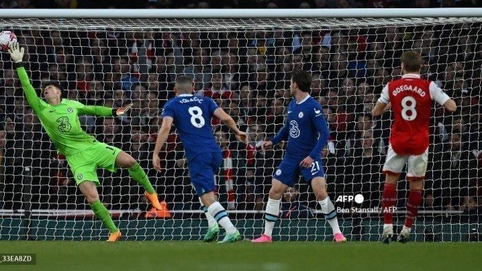 Gelandang Arsenal asal Norwegia Martin Odegaard (kanan) menyaksikan bola masuk ke gawang saat ia mencetak gol pembuka melewati kiper Chelsea asal Spanyol Kepa Arrizabalaga selama pertandingan sepak bola Liga Utama Inggris antara Arsenal dan Chelsea di Stadion Emirates, di London, pada 2 Mei 2023.