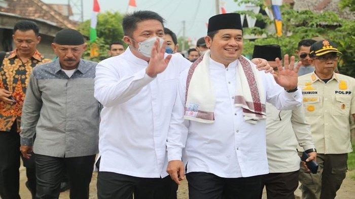 Gubernur Sumsel H Herman Deru merangkul Bupati Banyuasin H Askolani SH MH seraya melambaikan tangan menyapa masyarakat di Dusun 3 di Desa Perajin Banyuasin I Kabupaten Banyuasin, saat kegiatan peletakan batu pertama peningkatan pembangunan Mushola menjadi Masjid Al Amin, Jumat (22/7/2022) kemarin.