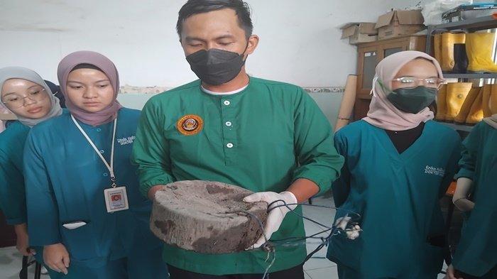Dokter Forensik Rumah Sakit Bhayangkara Moh Hasan Palembang, dr Indra menunjukan penampakan batu penggiling yang diikat ke perut korban yang ditemukan tewas di bawah Jembatan Tanjung Senai, Ogan Ilir, Selasa (20/8/2024)
