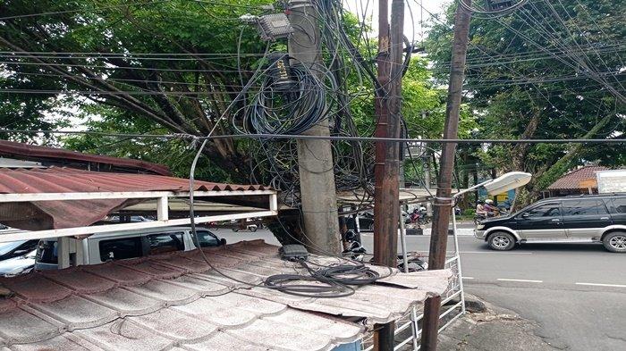 KABEL SEMRAWUT - Kondisi kabel yang tak tertata rapi di kawasan Jalan Radial, Palembang, menciptakan pemandangan yang memprihatinkan dan mengancam keselamatan warga. Kondisi serupa terjadi hampir di setiap sudut kota bahkan area pemumiman warga. Foto dibadikan Senin (5/5/2025).