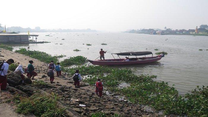 Sejumlah pelajar menggunakan transportasi air pergi sekolah di kawasan perairan Sungai Buayo, Kecamatan Jakabaring, Palembang, Jumat (27/10/2023). Setelah beberapa hari lalu kawasan kota Palembang dan Sumsel mulai diguyur hujan dan kabut asap karhutla mulai tipis, namun pagi ini kembali tebal, terutama di pinggiran kota Palembang.