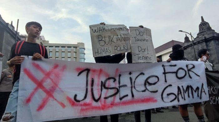 Massa aksi membentangkan kertas bertuliskan Wartawan Bukan Humas Polri ketika aksi demonstrasi meminta polisi mengusut kasus kematian GRO atau Gamma yang meninggal dunia ditembak polisi, di Mapolda Jateng, Kamis (28/11/2024).
