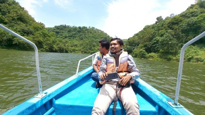 Seorang pengunjung swafoto di ujung depan perahu wisata di lokasi wisata air Bendungan Logung Kudus, Kamis (3/3/2022).