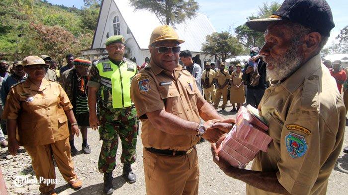 Plt Kepala Dinas DPMK Kabupaten Tolikara Noak Tabo menyerahkan dana desa kepada kepala kampung di Distrik Wugi.