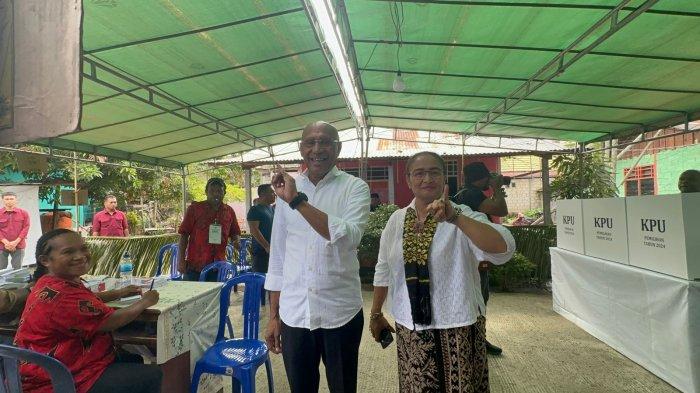 MENCOBLOS - Calon Gubernur Papua, Benhur Tomi Mano didampingi istri menunjukkan jari kelingking bertanda tinda usai menggunakan hak pilihnya di TPS 04 yang berada di dekat kediamannya di Distrik Abepura, Kota Jayapura, Provinsi Papua, Rabu (27/11/2024).