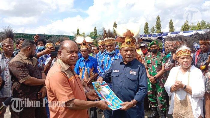 ADAT - Asisten Bidang Pemerintahan dan Hukum Sekda Provinsi Papua, Doren Wakerkwa saat menyerahkan SK Kodefikasi 14 Kampung Adat kepada Bupati Jayapura, Mathius Awoitauw, Jumat (19/8/2022)