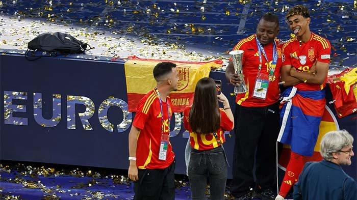 Penyerang dan bintang muda Spanyol, Lamine Yamal, merayakan bersama keluarganya setelah memenangkan pertandingan sepak bola final Piala Eropa 2024 antara Spanyol dan Inggris di Stadion Olimpiade Berlin, Jerman, Senin (15/7/2024) dini hari WIB. AFP/ODD ANDERSEN