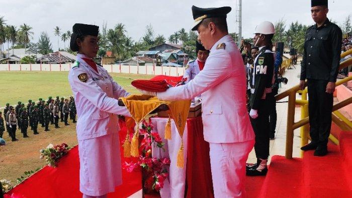 Bupati Kaimana, Freddy Thie saat menyerahkan bendera merah putih ke anggota Paskibra untuk dikibarkan