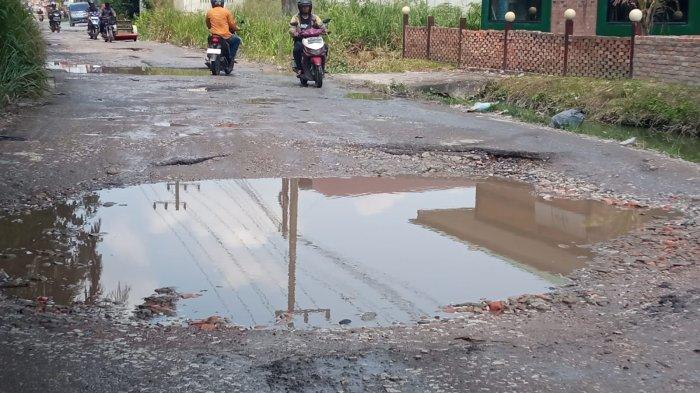 Pengendara melintasi Jalan Bangau Sakti Pekanbaru yang rusak dan penuh lubang, Selasa (6/8/2024). (TRIBUN PEKANBARU/THEO RIZKY).