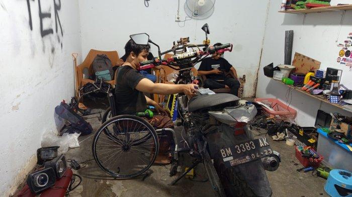 Indra yang lumpuh memperbaiki sepeda motor.