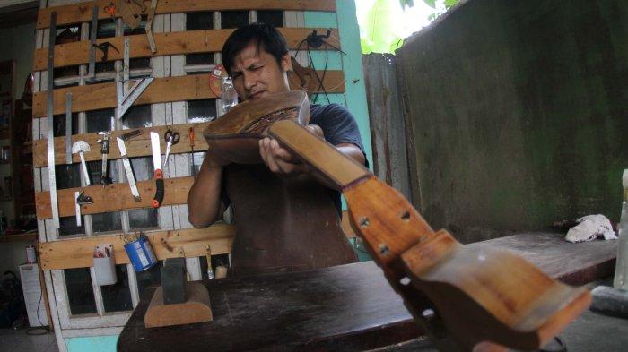 Pengrajin alat musik gambus Melayu, Robithah Irawan (34) tengah bekerja di workshop nya Jalan Kartama Pekanbaru, Jumat (9/8/2024). 