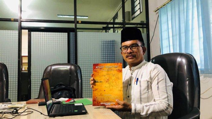 Kepala Dinas Sosial Siak Wan Idris memegang naskah buku Perjuangan Tengku Buwang Asmara yang berjudul Muslihat Bermartabat, Jumat (22/4/2022) di ruangan kerjanya.