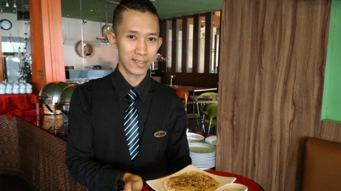 Seorang pelayan restoran menyajikan lempeng sagu khas Riau.