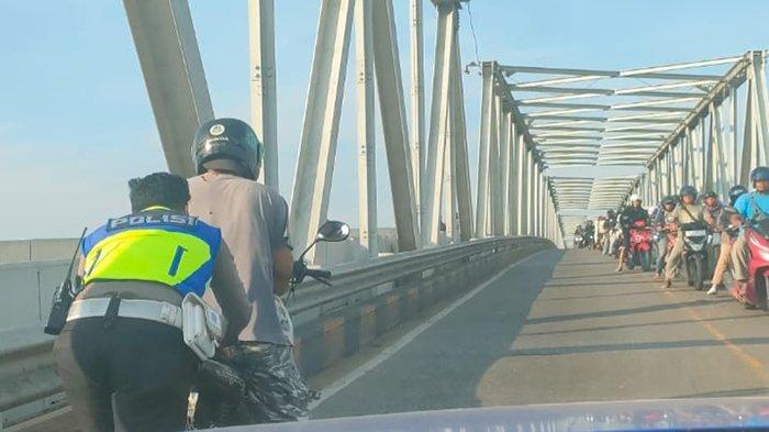 Anggota Satlantas Polres Singkawang, Briptu Herianto saat membatu pengendara motor mogok di Jembatan Kapuas Satu Kota Pontianak, Jum'at 28 Juli 2023.