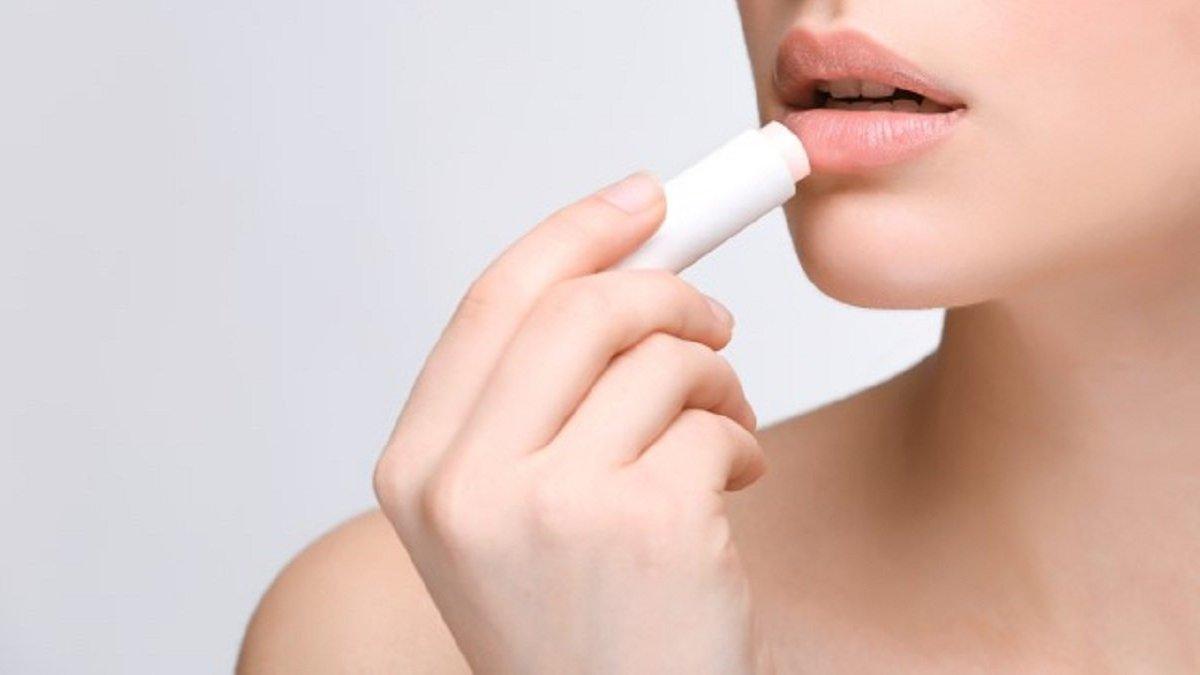 Ilustrasi wanita mengaplikasikan lip balm yang mengandung SPF.