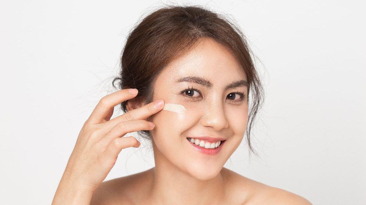 Mengaplikasikan sunscreen ke wajah.