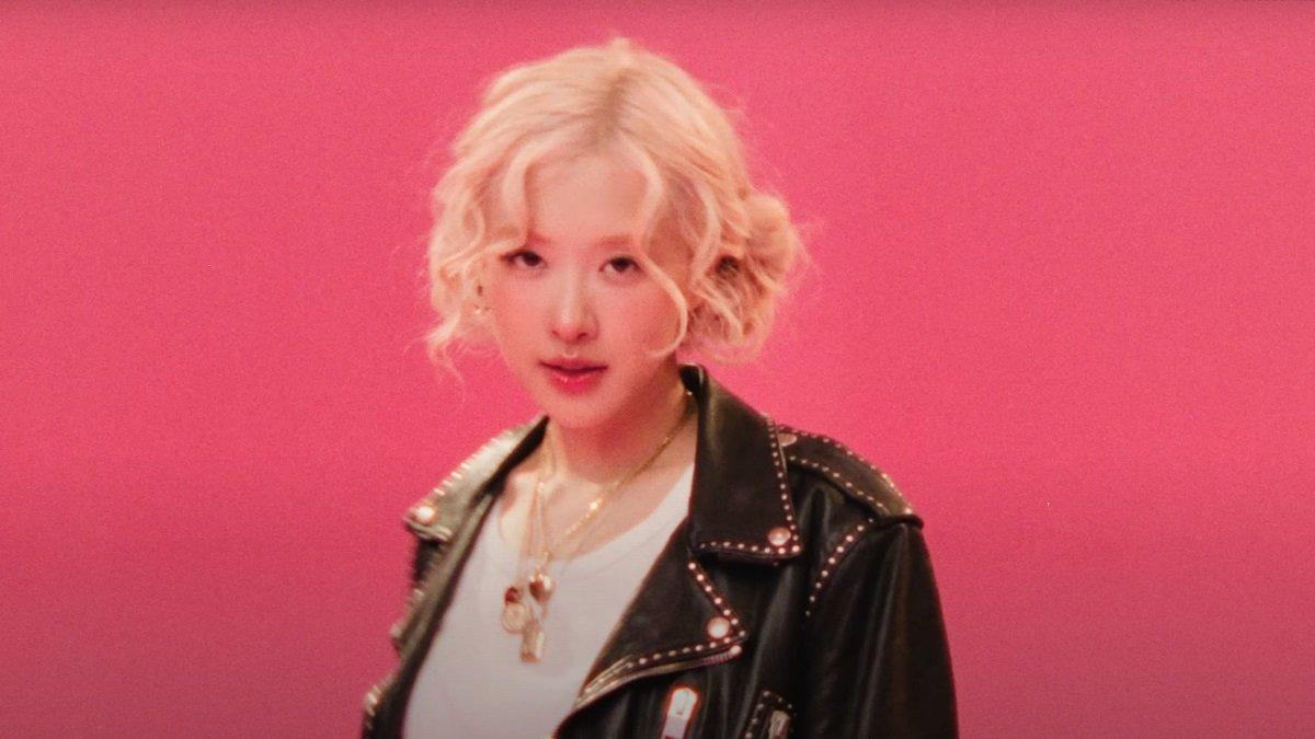 Rose BLACKPINK tampil dengan rambut blonde diikat curly double bun, dipadukan sneakers putih dan kaus kaki merah.