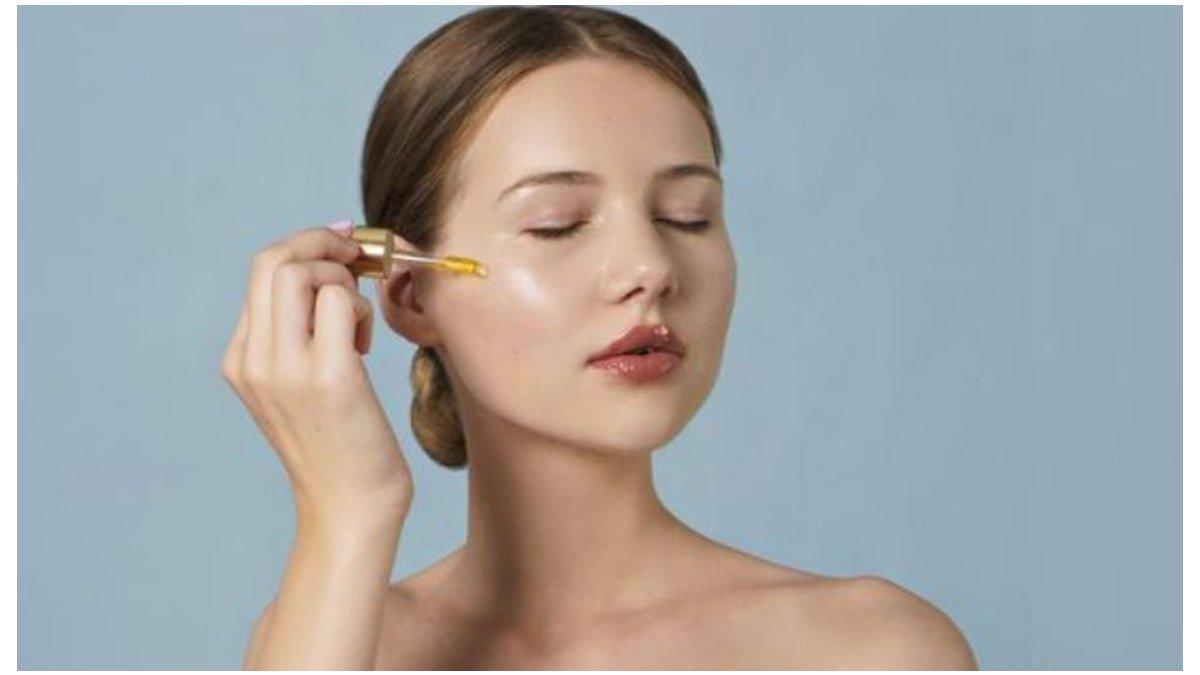 Ilustrasi wanita menggunakan serum pada wajah.