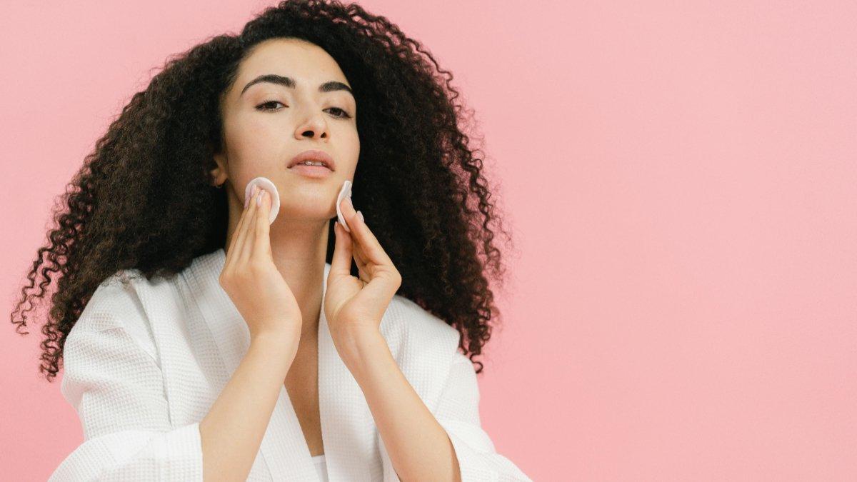 Ilustrasi wanita membersihkan wajah menggunakan makeup remover.