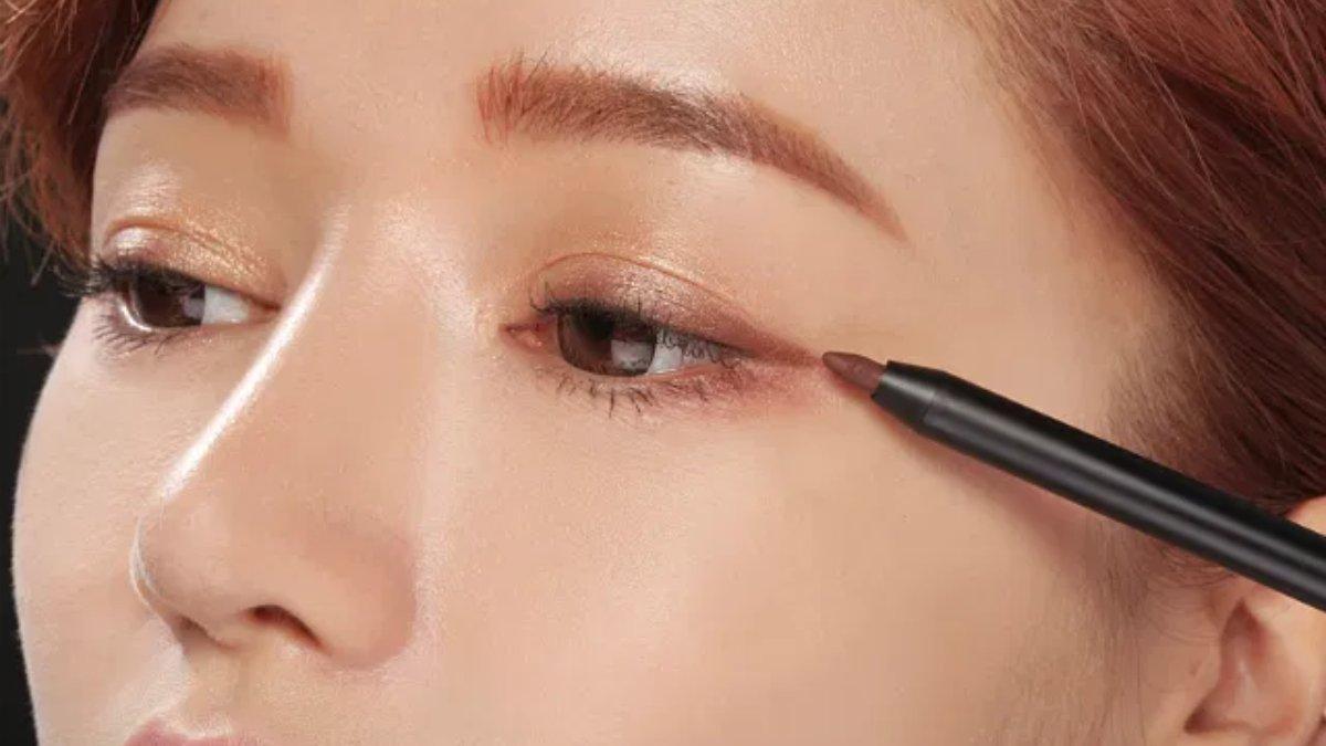 Ilustrasi wanita menggunakan eyeliner cokelat.