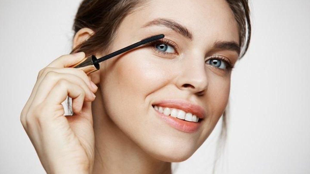 Ilustrasi wanita menggunakan mascara dengan formula waterproof.