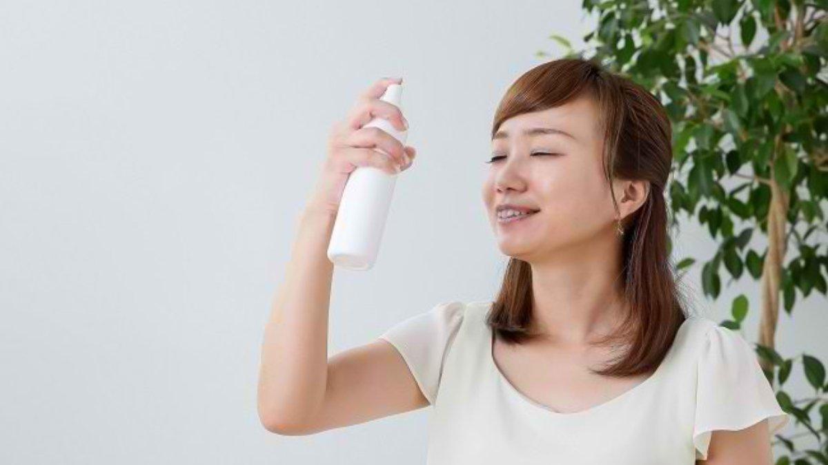 Ilustrasi wanita menyemprotkan setting spray secara merata ke seluruh wajah.