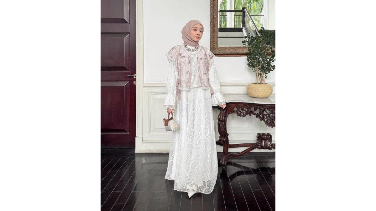 Meirani Amalia tampil stylish dan feminim mengenakan dress brokat putih dipadukan dengan vest lace.