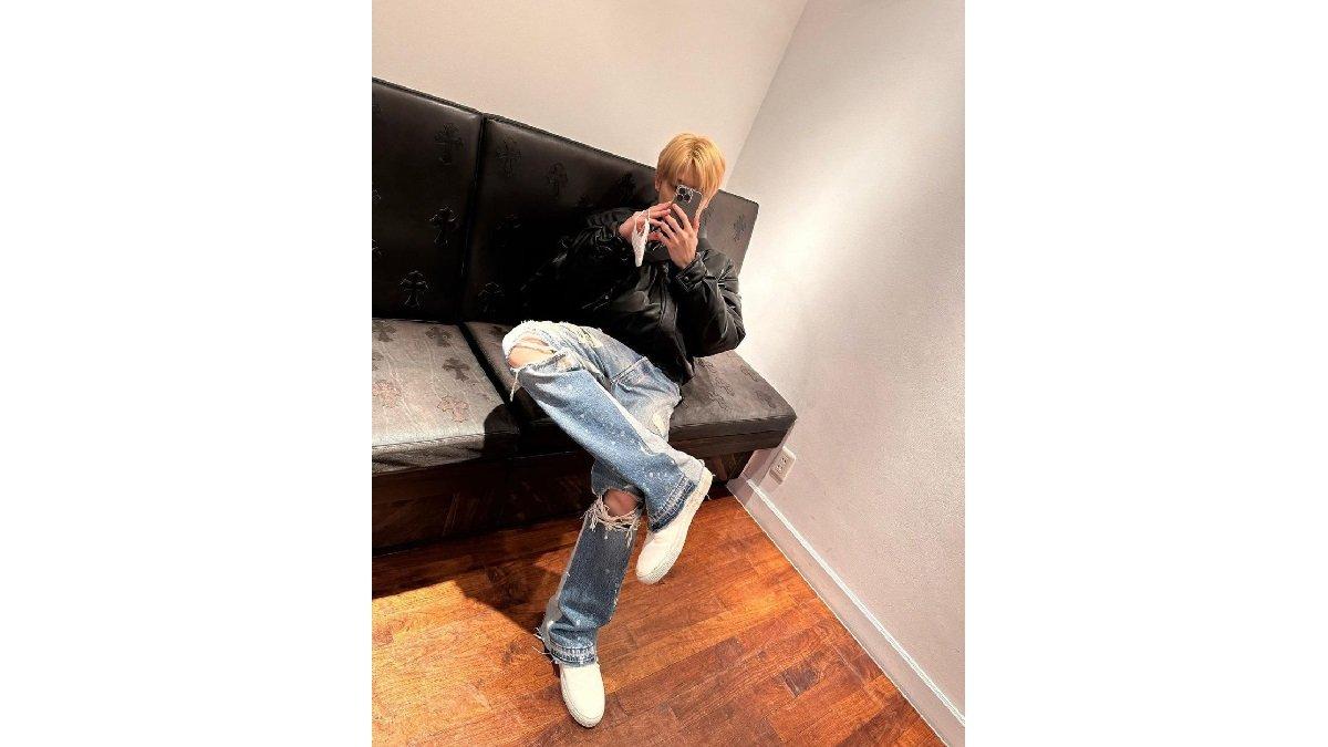 Padu Padan Outfit Denim ala Jaehyun NCT mengenakan Leather Bomber Jacket, Ripped Print Blue Jeans, dan White Sneaker.