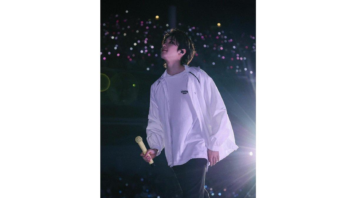 Wonwoo Seventeen mengenakan Basic Kaus, Jaket Putih, dan Celana Hitam Parasut.