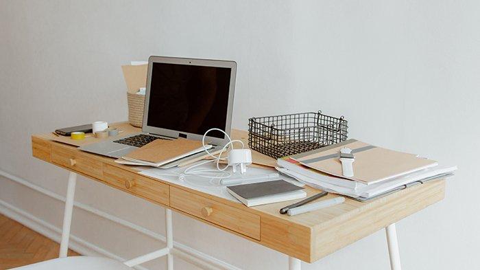 Ilustrasi laptop dan charger di atas meja yang tidak terpapar cahaya matahari langsung
