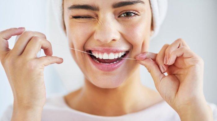 Flossing menggunakan benang gigi.