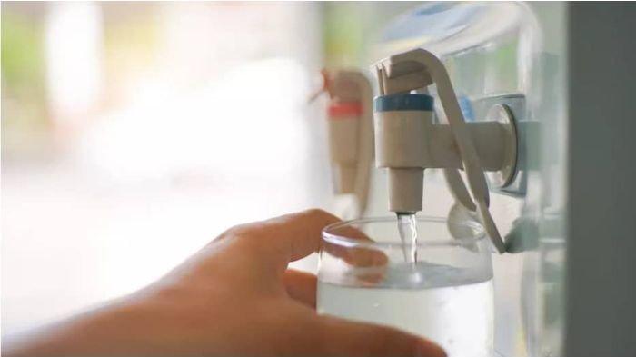 Ilustrasi mengambil segelas air dingin dari dispenser.