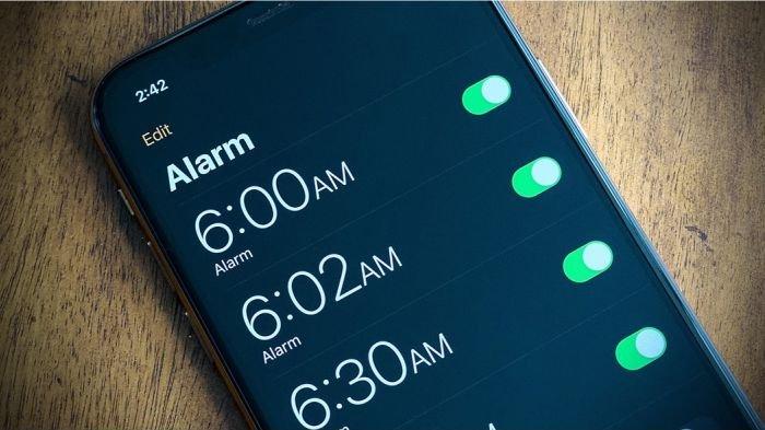 Ilustrasi memasang alarm di HP untuk bangun dari tidur