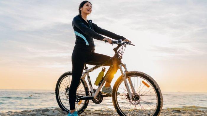 Perempuan bersepeda untuk menurunkan berat badan.