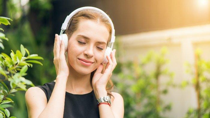 Ilustrasi pemakaian headset bando untuk mendengarkan musik