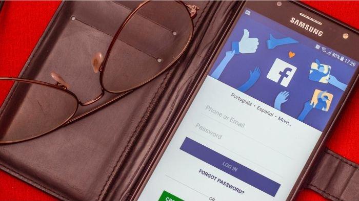Ilustrasi pengguna HP sedang membuka laman login Facebook