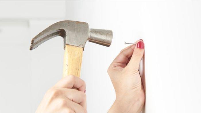 Ilustrasi memalu paku ke tembok, gunakan karton atau kardus untuk meredam getarannya